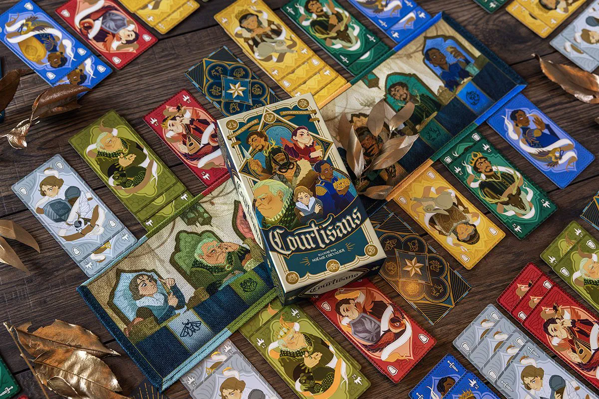 Boîte de Courtisans posée sur le tapis en tissu, entourée de cartes Courtisan des six familles aux bordures dorées